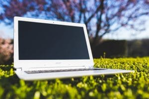 white laptop on a green meadow